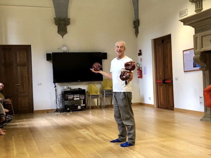 Instructor Jim Calder lecturing the class, holding three traditional Commedia dell'Arte masks.